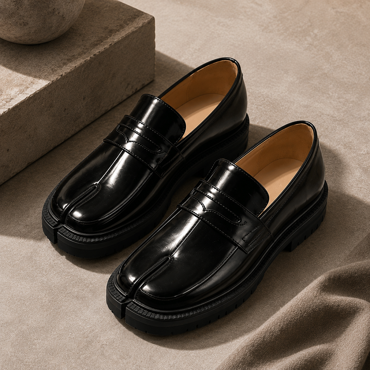 Black glossy split-toe slip-on leather flats on neutral stone background